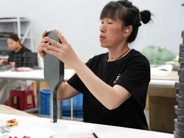 Mozkuib worker checking the surface of a pickleball paddle