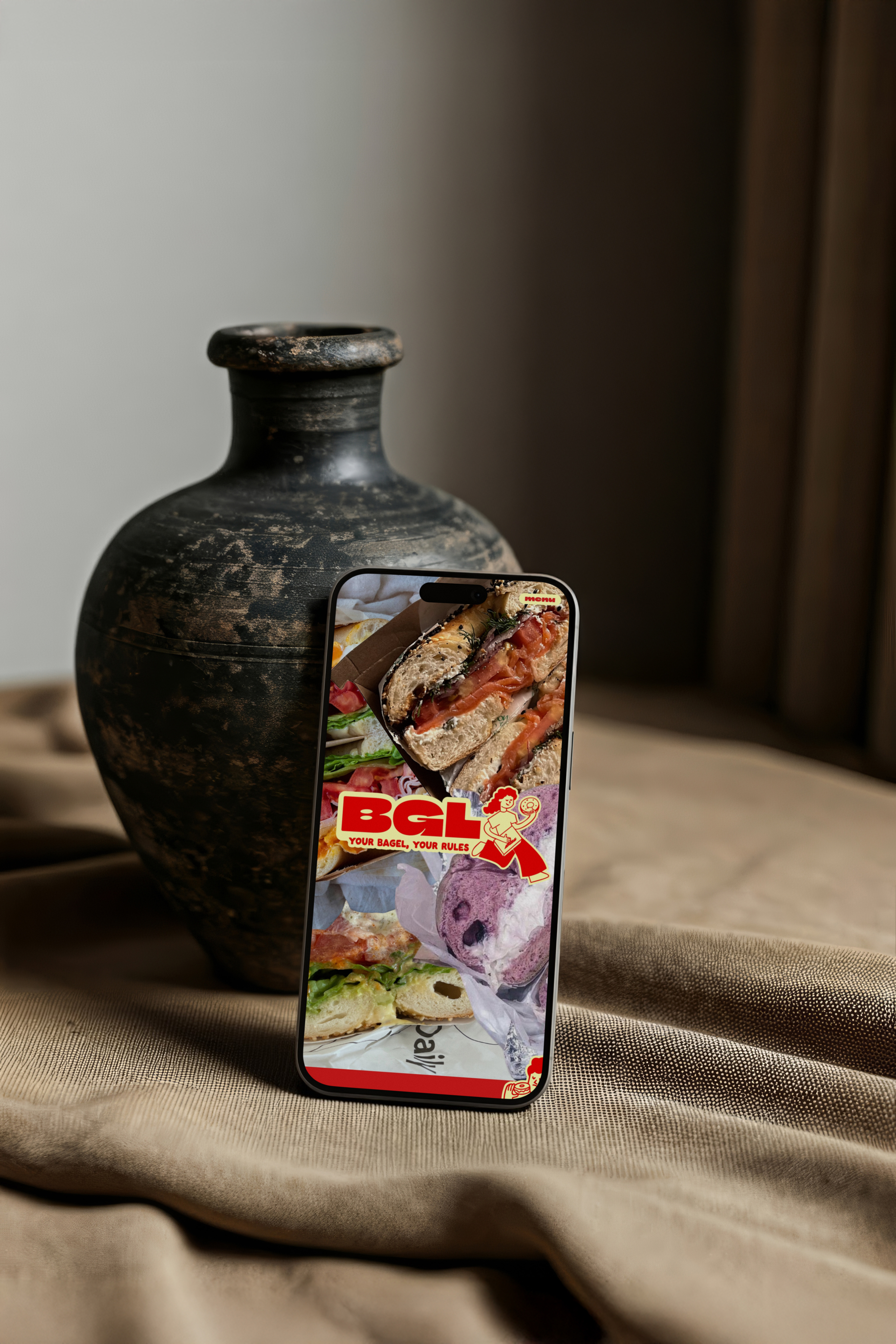 Phone mockup of a BGL social media post, propped against a dark ceramic vase