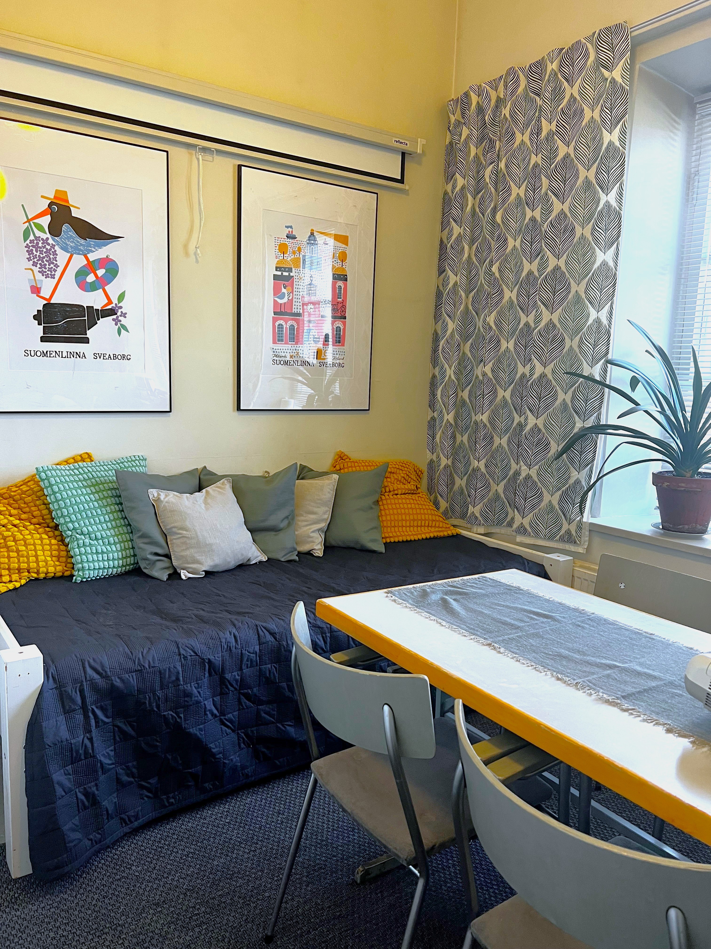 Sofa with cushions, table and posters on the wall in the fireplace room