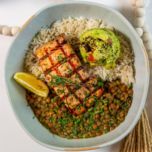 Bowl of salad with fried halloumi cubes, green apple slices, fresh dill, spinach leaves, and a lemon wedge.