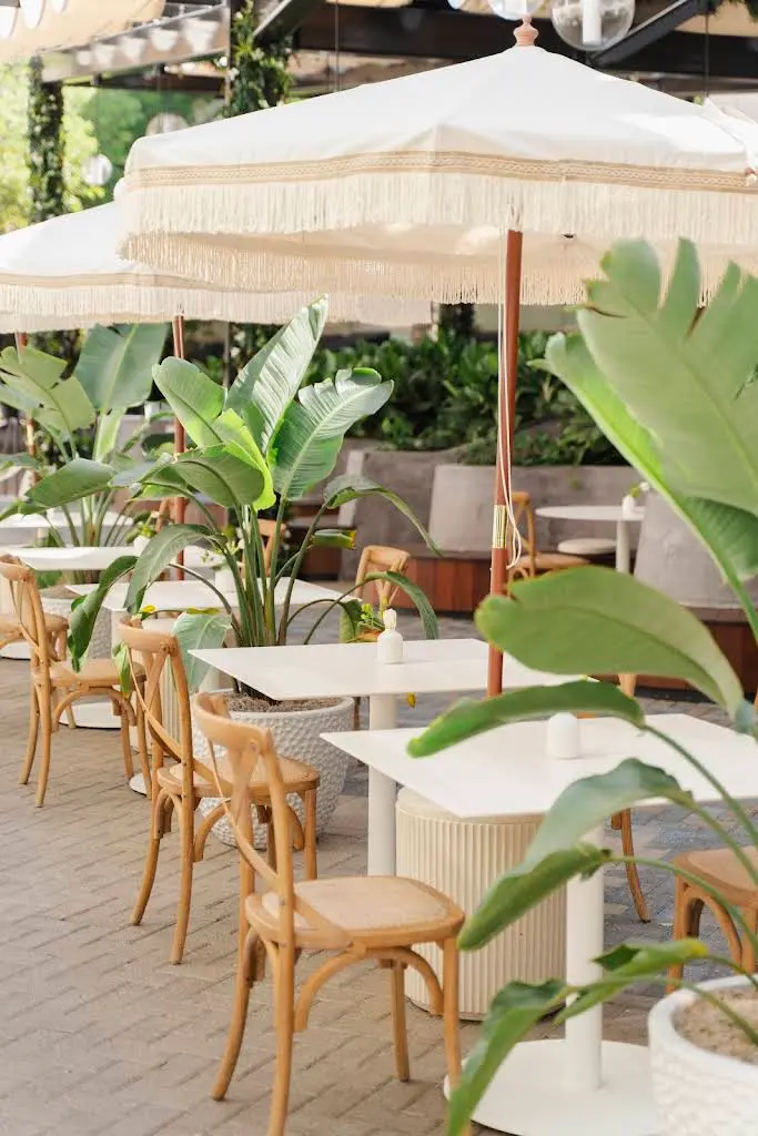 Golden brown croissant on a rectangular white plate next to a cup of latte with leaf-shaped latte art.