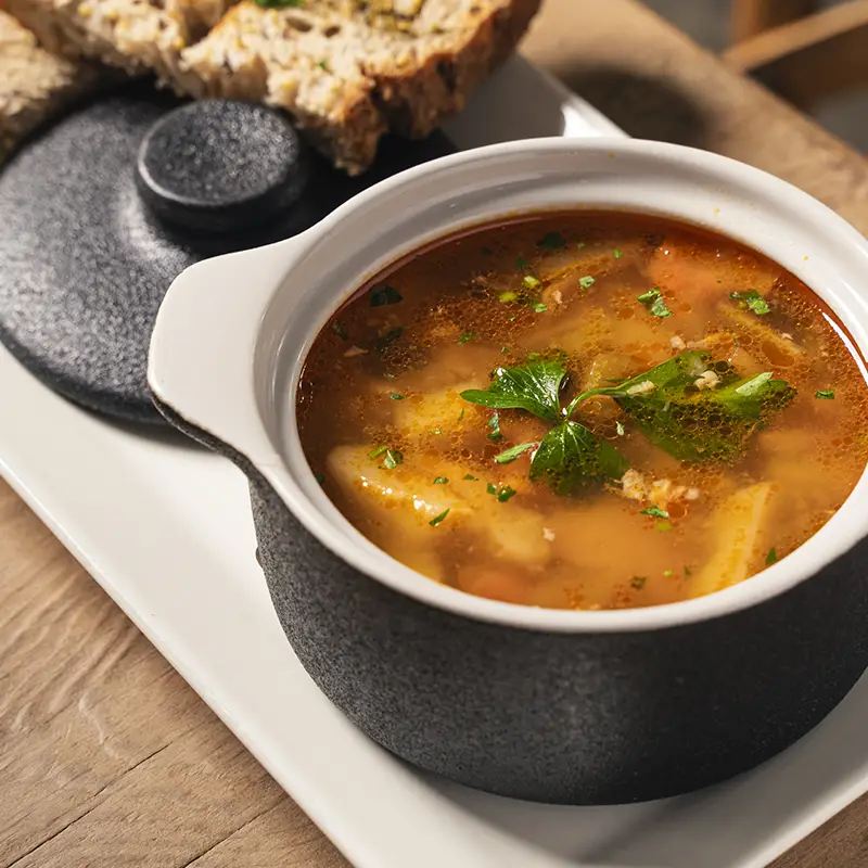 Burrata cheese in tomato sauce garnished with basil leaves, served with toasted bread slices.