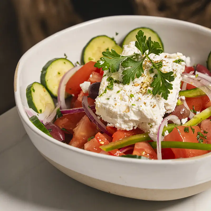 Burrata cheese in tomato sauce garnished with basil leaves, served with toasted bread slices.