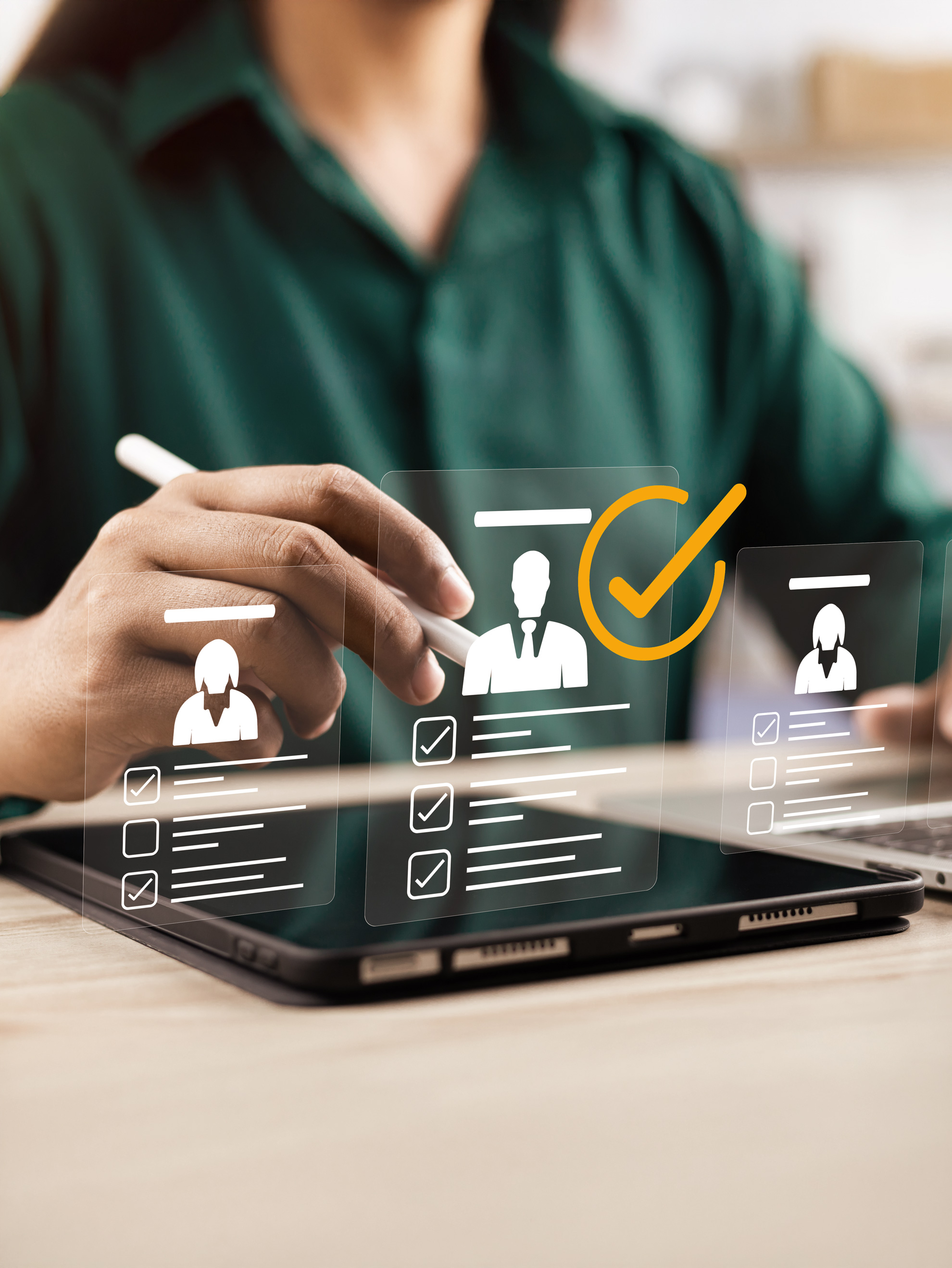 Person mit Stift wählt digitalen Profilkandidaten auf Tablet mit hervorgehobenem Kontrollhäckchen.