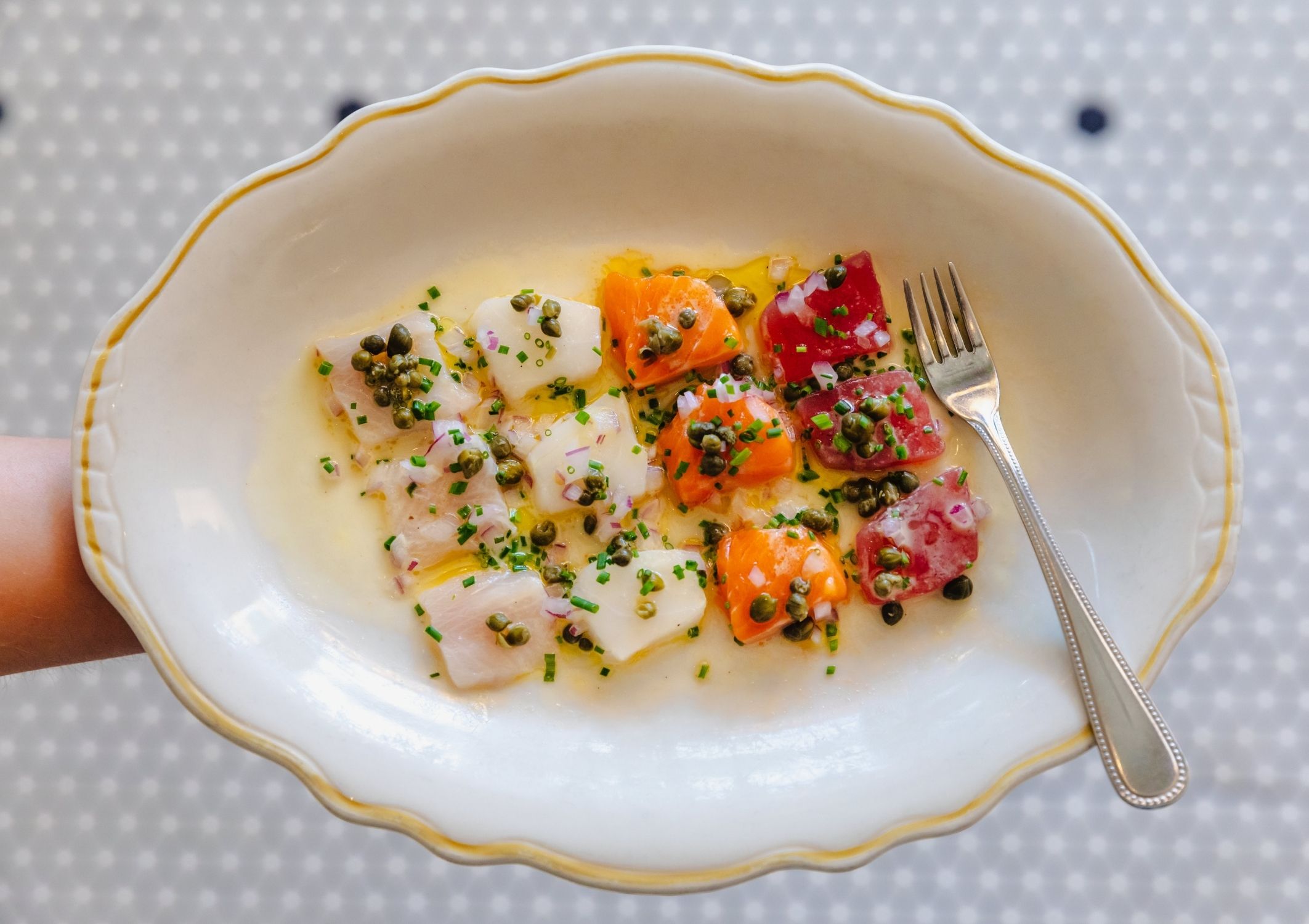 A plate of fresh crudo with capers, onions and lemon viniagrette