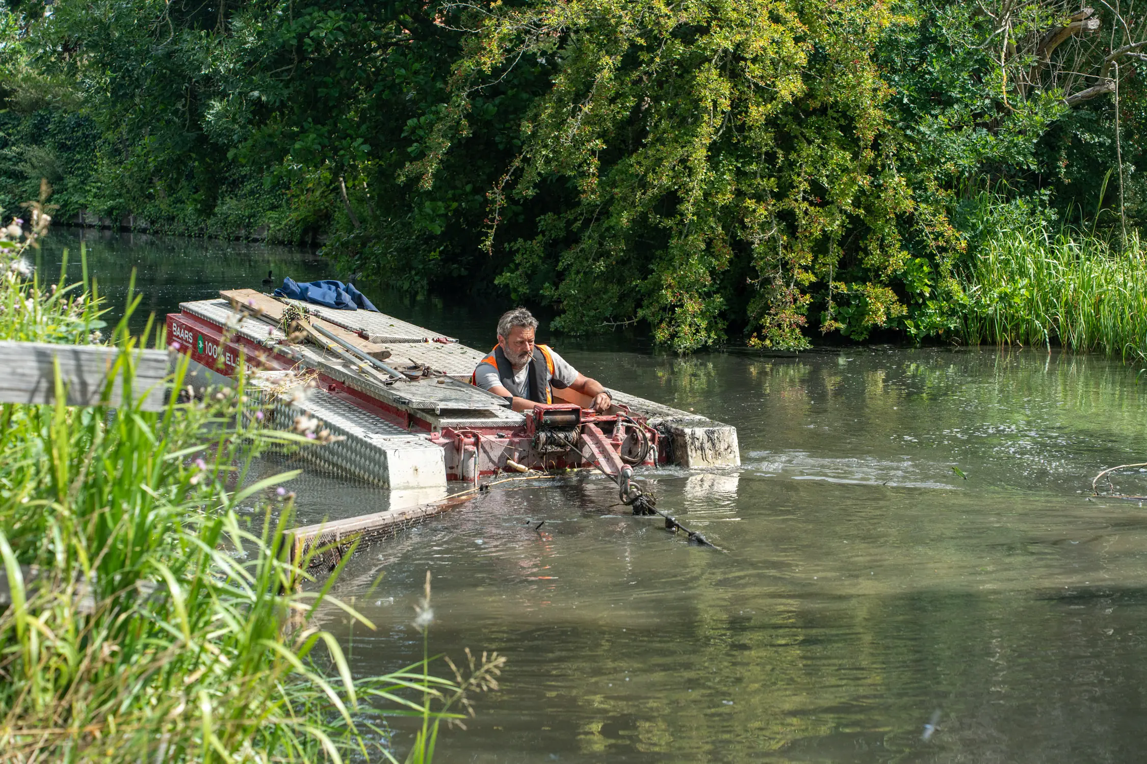 Elektrische baggerboot van Baars in actie tussen het groen in Schiedam tijdens duurzaam onderhoud van de watergang
