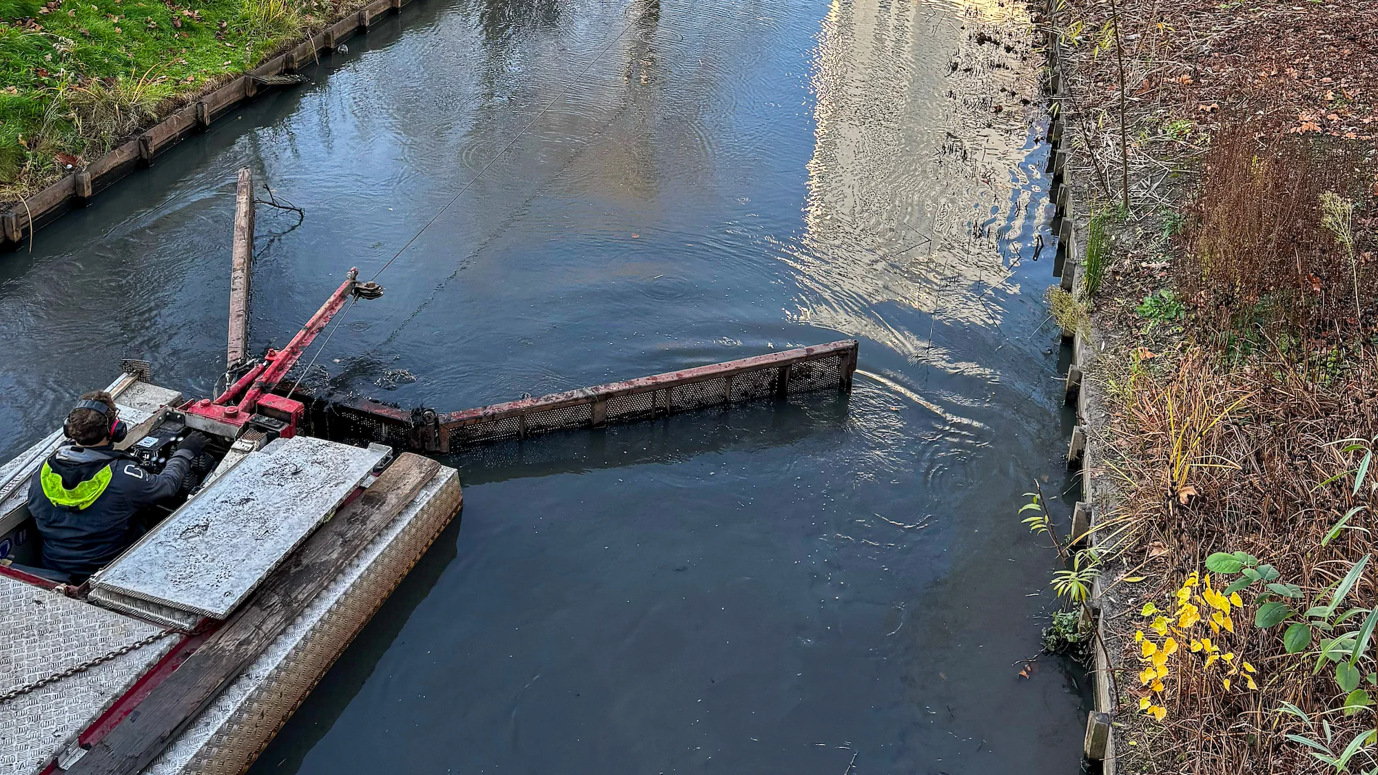 Close-up van de baggerbeugel die de sliblaag losmaakt en transporteert in de nauwe watergang van het Museumpark.
