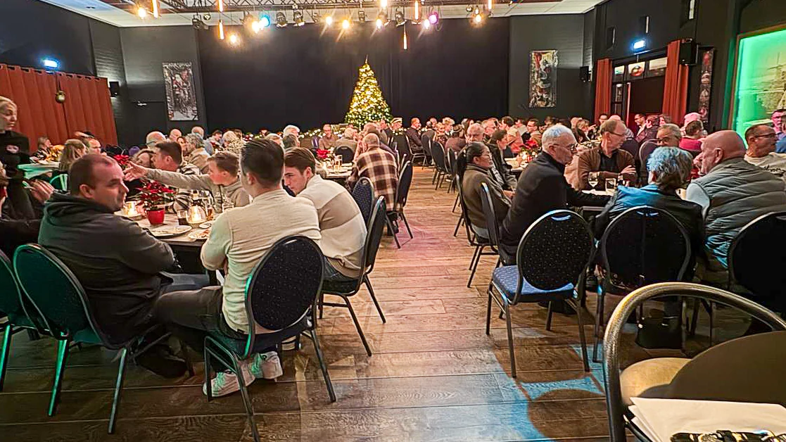 Overzicht van het Baars-kerstdiner met volle tafels en kerstboom op de achtergrond