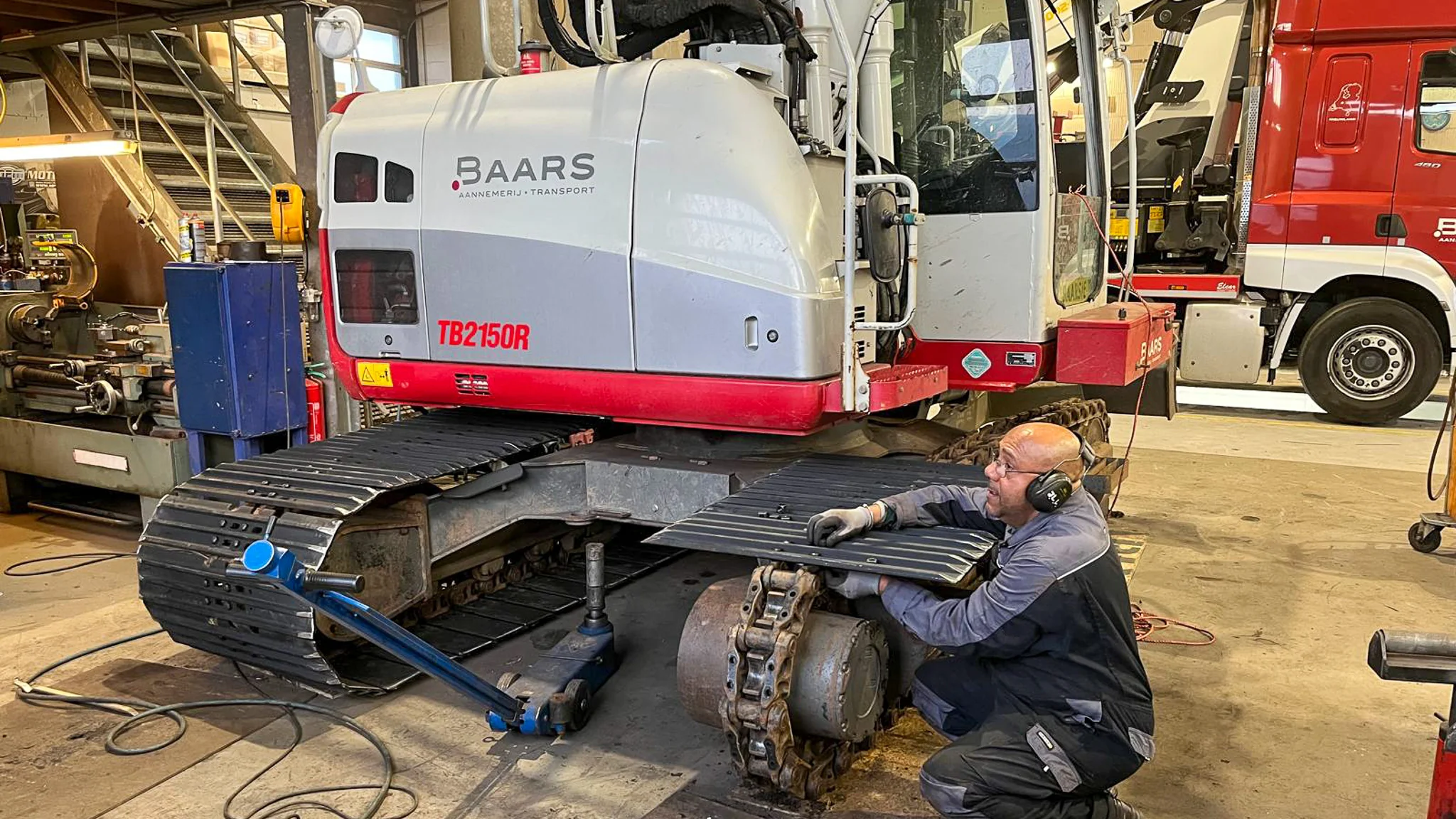 Monteur vervangt rupsplaat aan de Takeuchi in de werkplaats van Baars