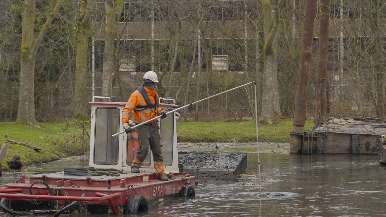 Baars medewerker voert meting uit vanaf ponton tijdens saneringswerkzaamheden in watergang