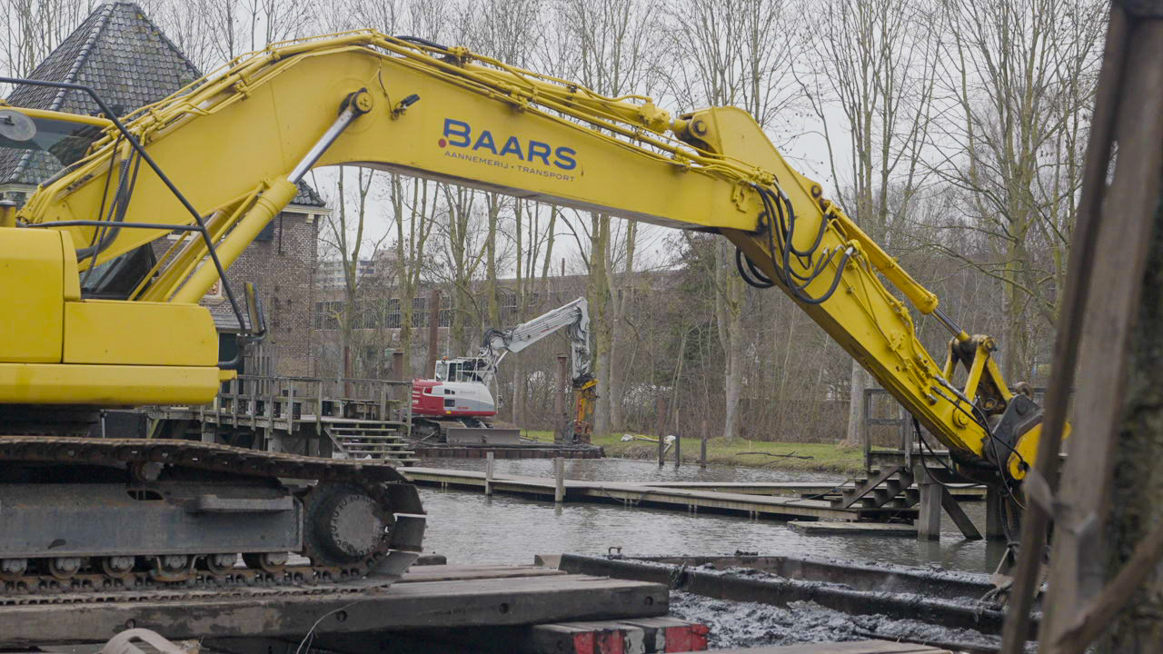 Graafmachine van Baars laadt vervuilde waterbodem op ponton tijdens saneringswerkzaamheden bij het Kruithuis in Delft