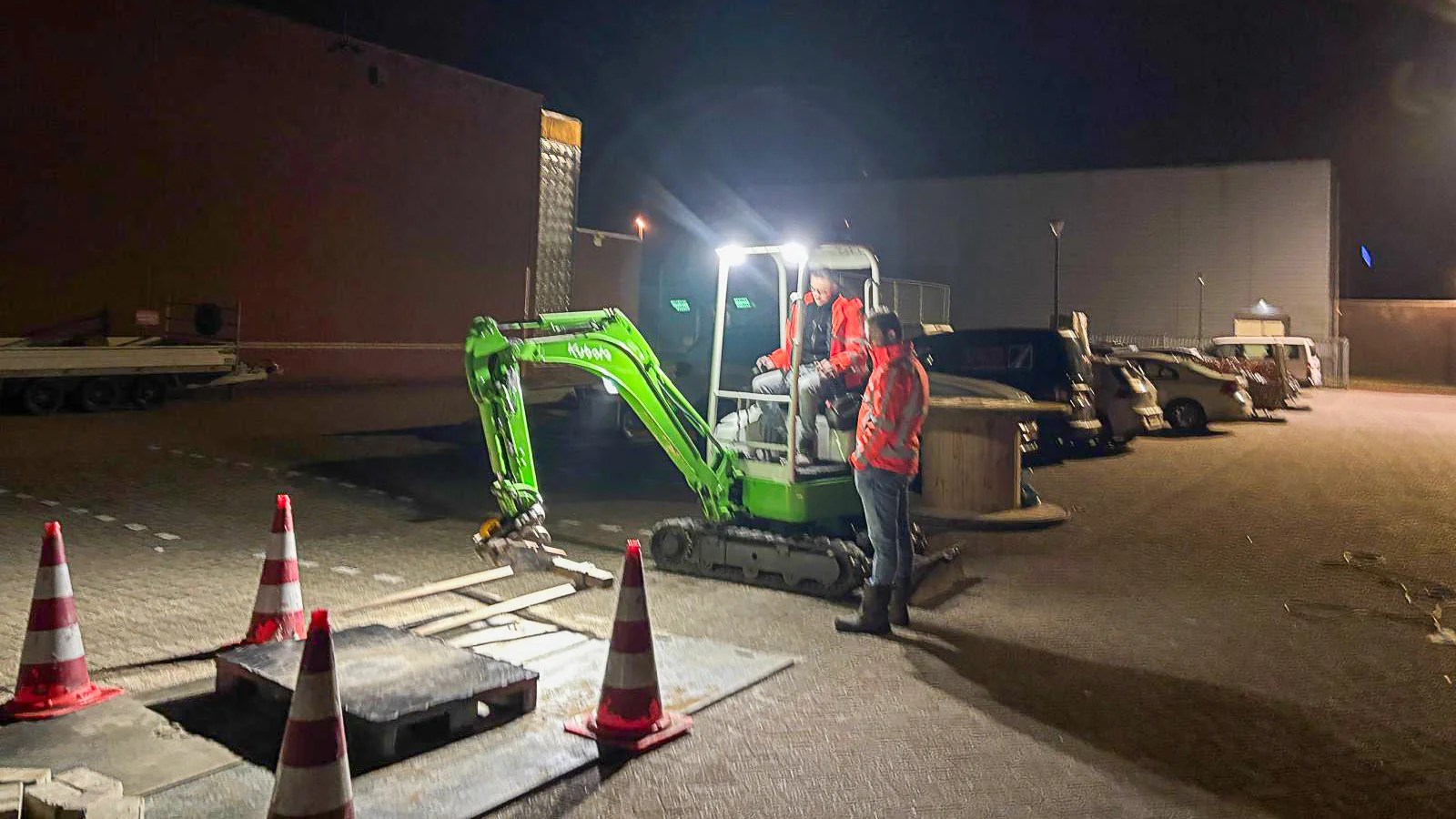 Medewerker begeleidt leerling op minigraver tijdens machinistenworkshop bij Gomarus Hulp in Uitvoering