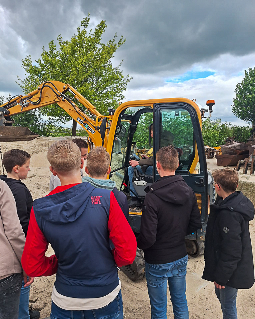 Leerlingen bekijken en bedienen een minigraafmachine tijdens een bezoek aan Baars in Nieuwland.
