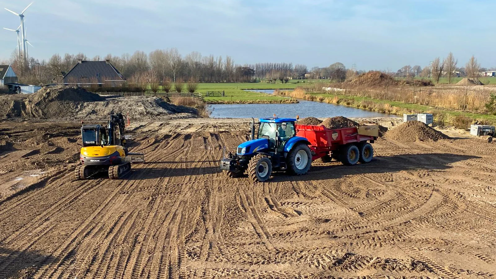 Graafmachine en trekker voeren grondwerk uit tijdens het bouwrijp maken.