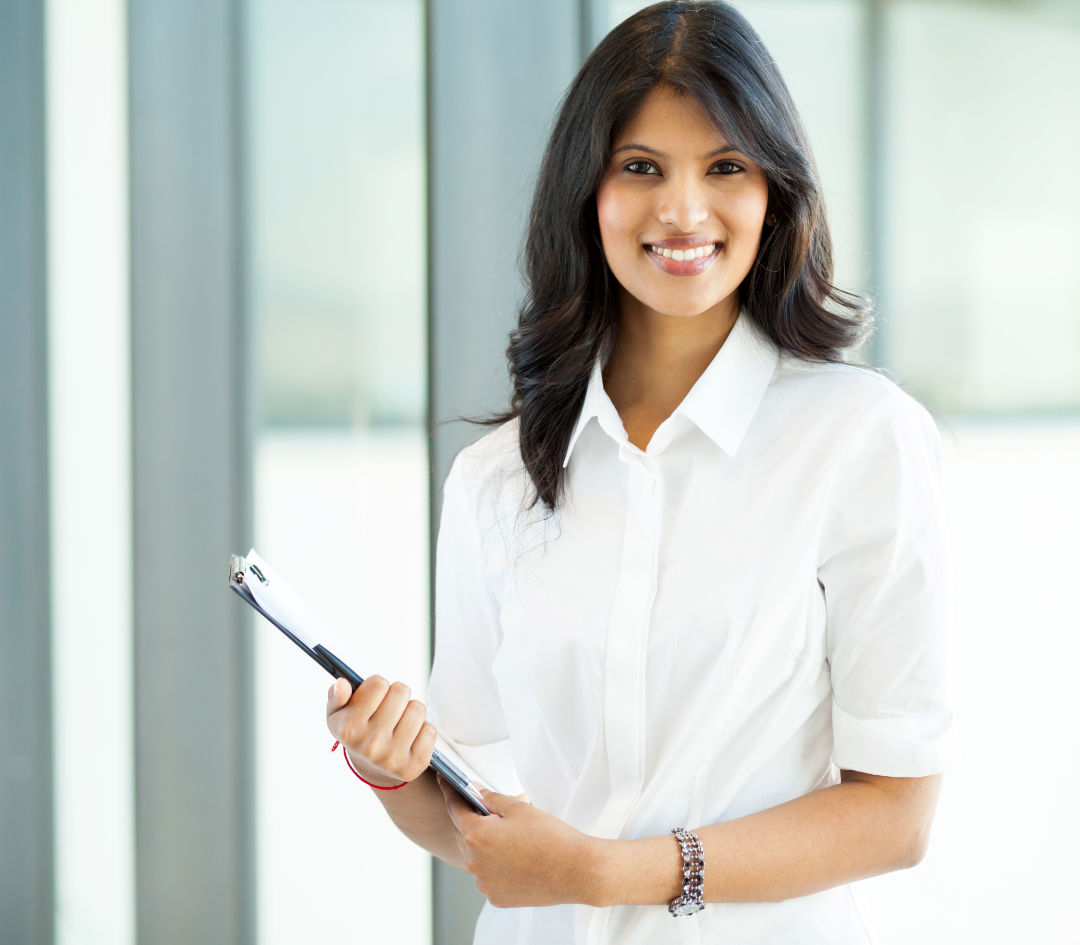 Confident woman in white shirt holding laptop.