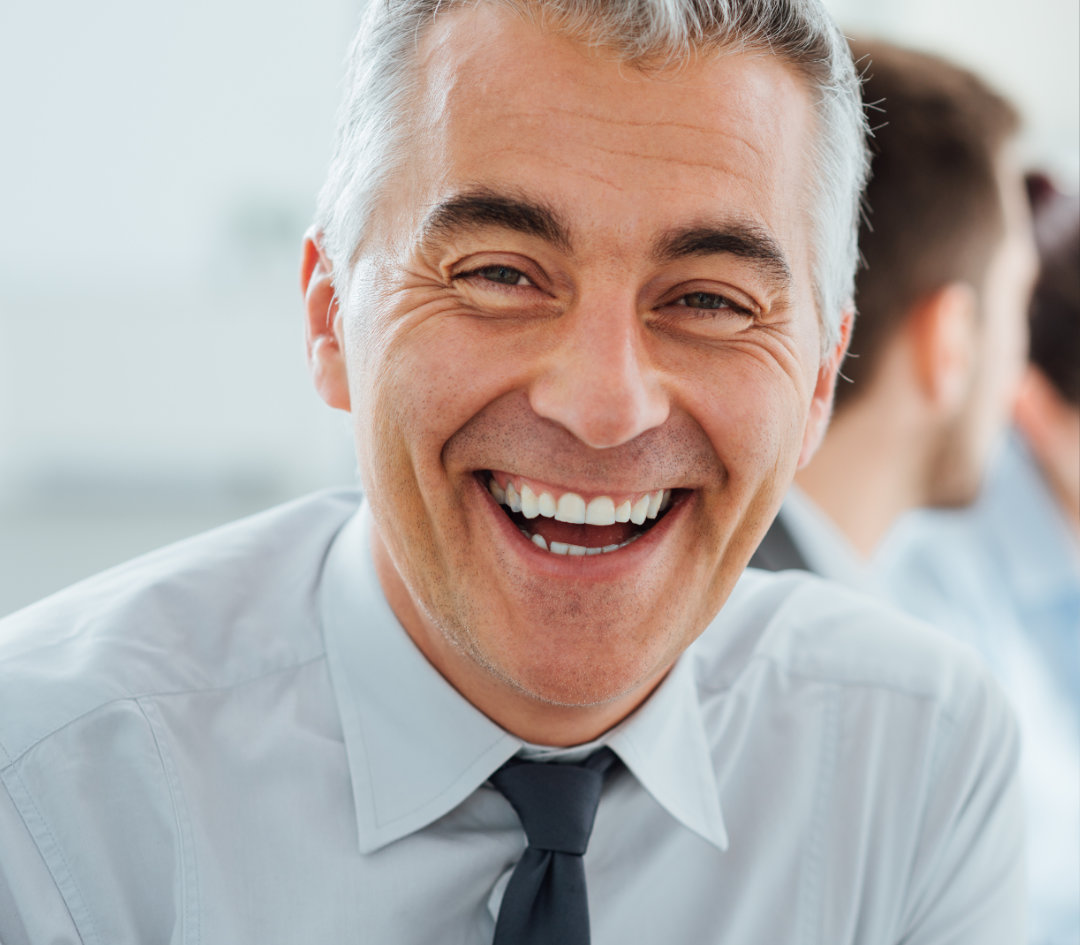 Woman in business attired reaching across table and confidently shaking a mans hand.