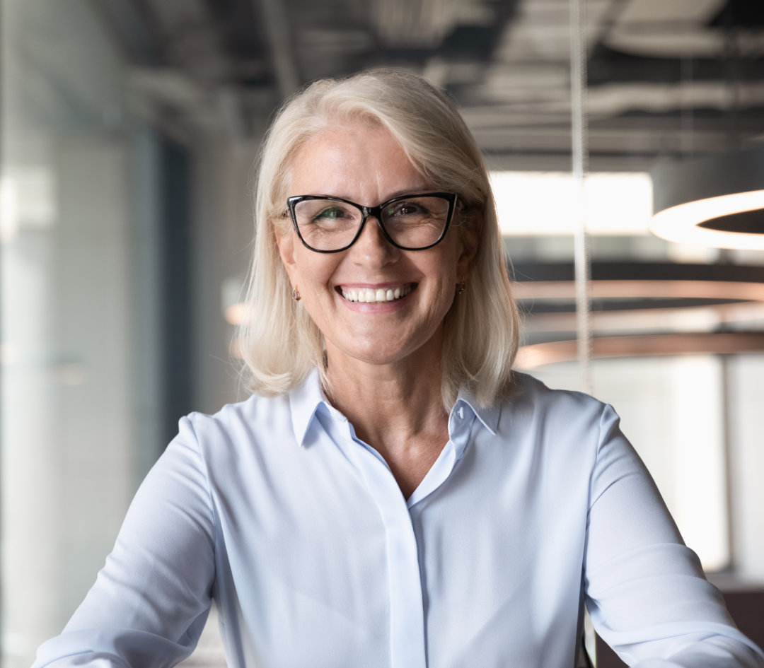 Confident woman in white shirt holding laptop.