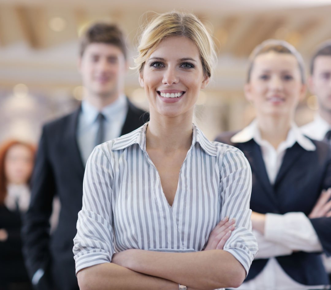 Confident woman with blonde hair, folded arms, and smiling.