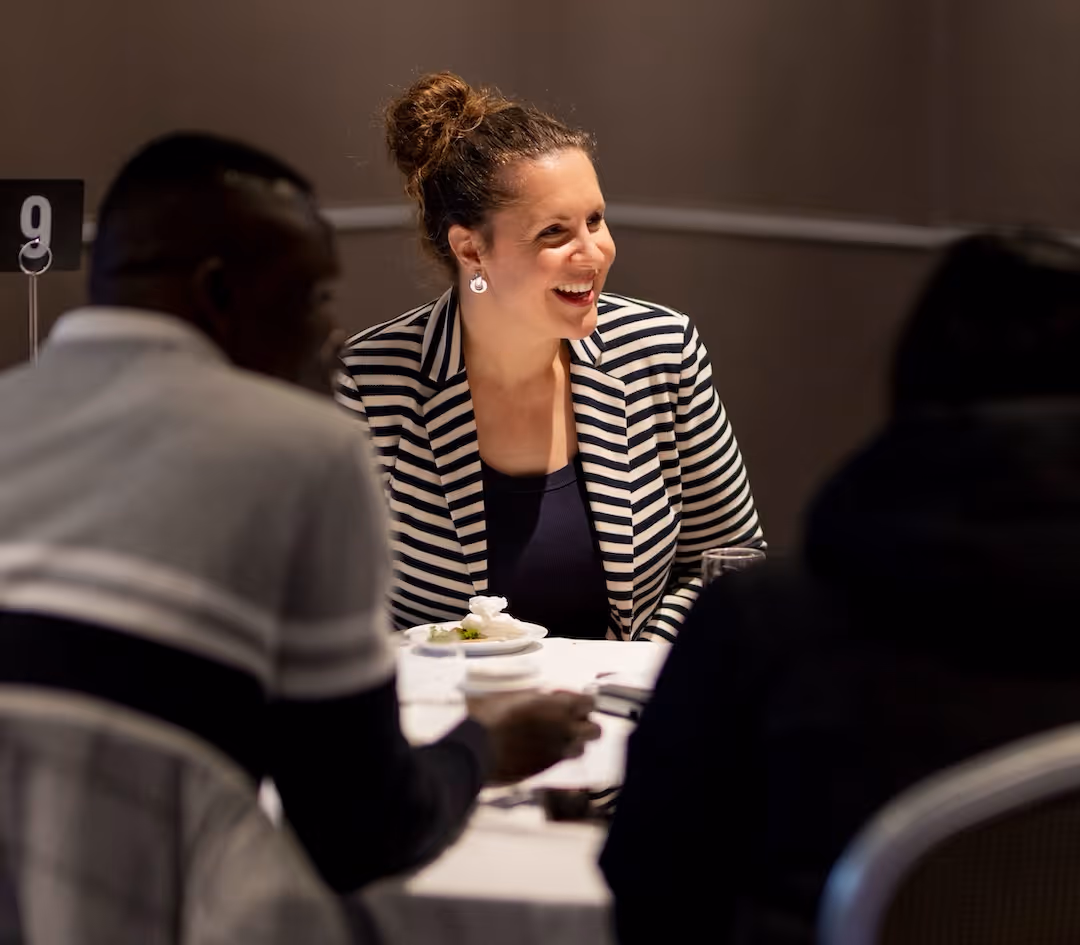Woman in business attired reaching across table and confidently shaking a mans hand.