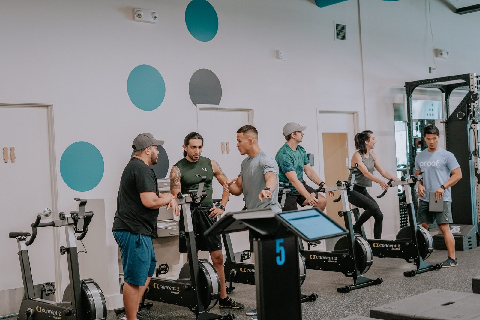 A proof3 coach works with a small group of members on bikes and training stations.