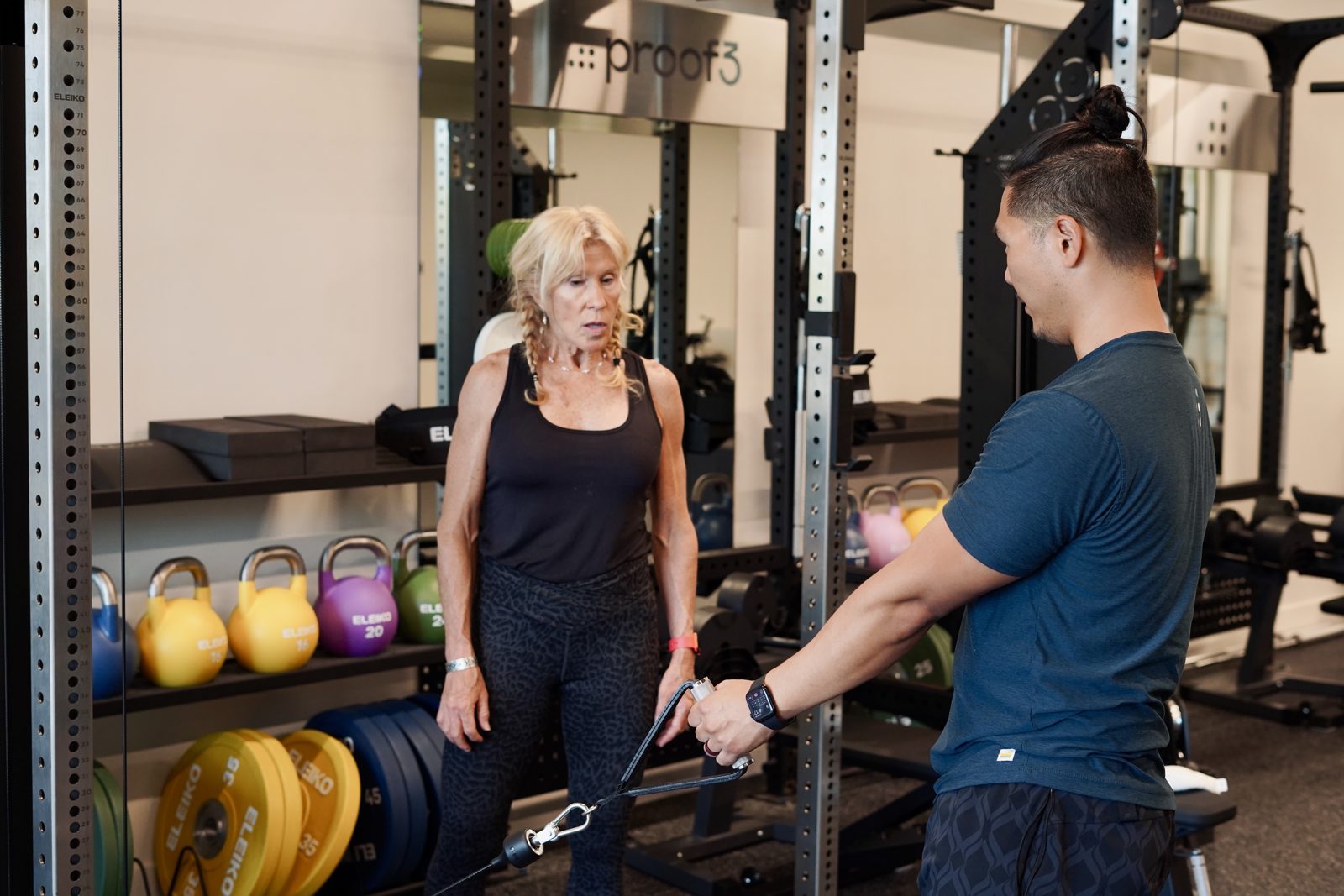 A proof3 coach demonstrates a cable exercise for a member.