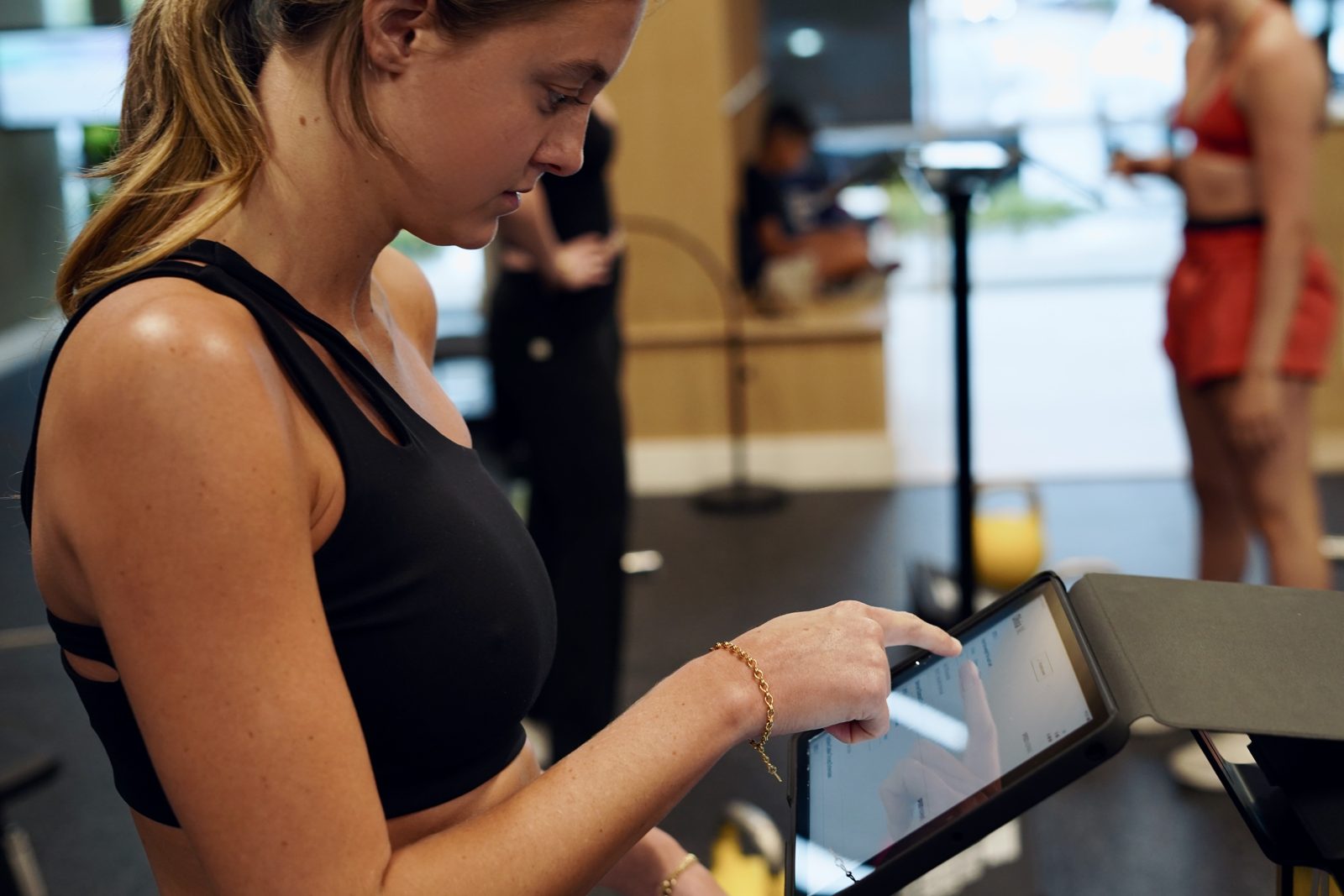 A member checks her workout on a training-station tablet.