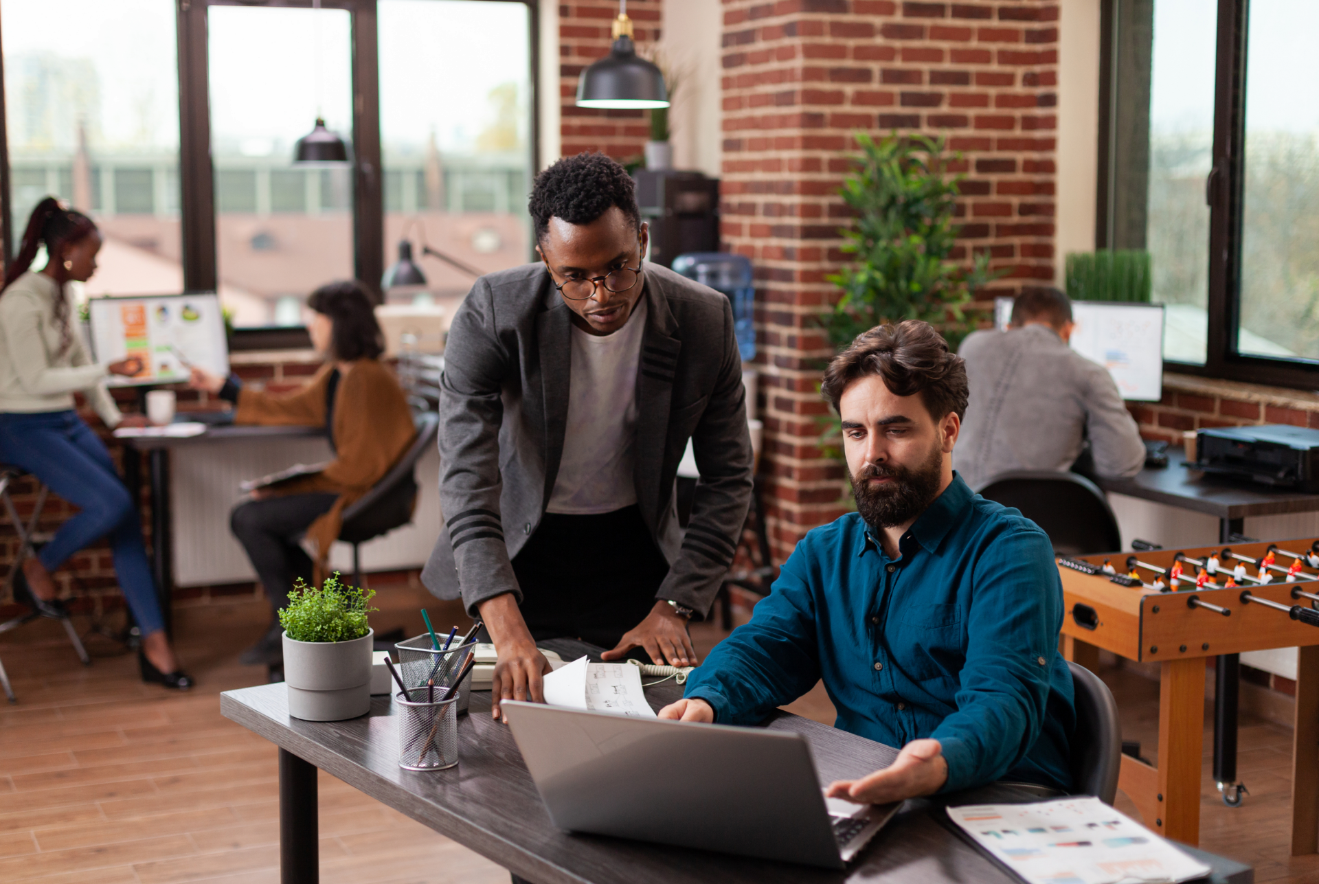 Two colleagues reviewing a content workflow together on a laptop in an open office