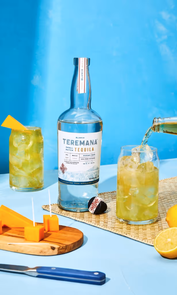 Bottle of Teremana Tequila prominently displayed, capturing its clear labeling and unique bottle shape, with hints of agave plants in the background