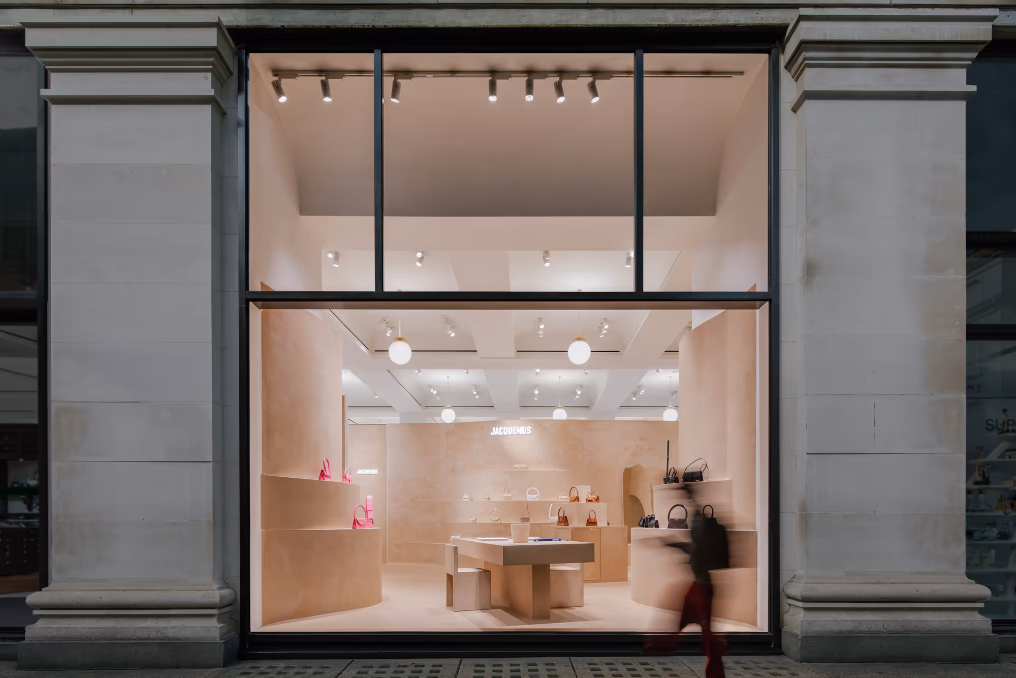 Interior of Jacquemus' London store at Selfridges, featuring organic, sculptural shapes. Reddish-brown display shelves and furniture made from terracruda clay blend seamlessly with walls, evoking Provençal architecture and the brand's southern French roots.