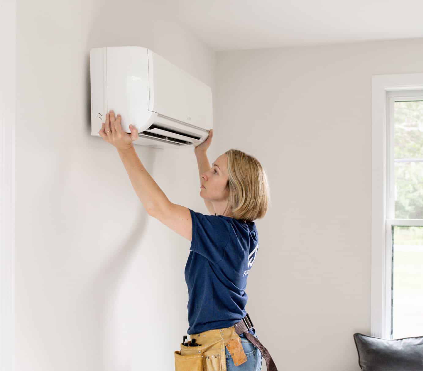 Forge HVAC technician hanging a mini-split head in a massachusetts home
