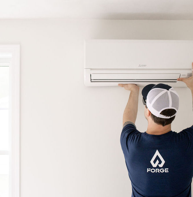 Forge HVAC technician hanging a mini-split head in a massachusetts home