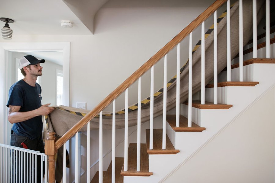 A Forge installer laying a drop cloth over the stair rail