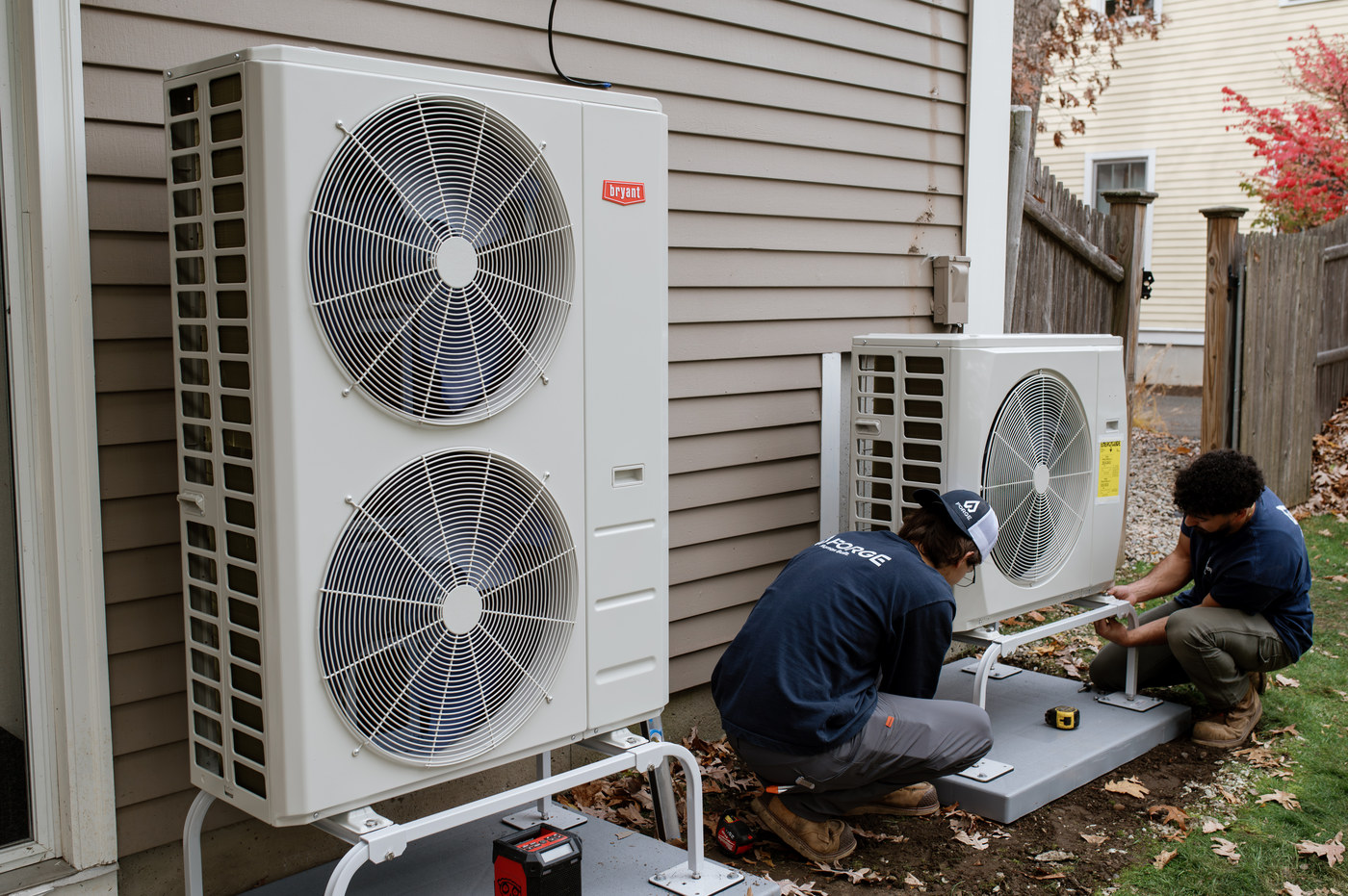 Two Forge installers connecting a pair of outdoor heat pump units