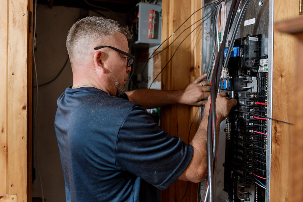A Forge electrician working in an open electrical panel