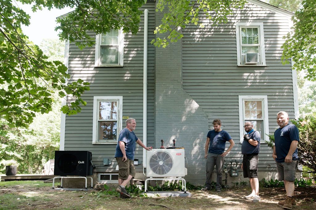 The Forge crew beside two finished outdoor heat pump units at a Massachusetts home