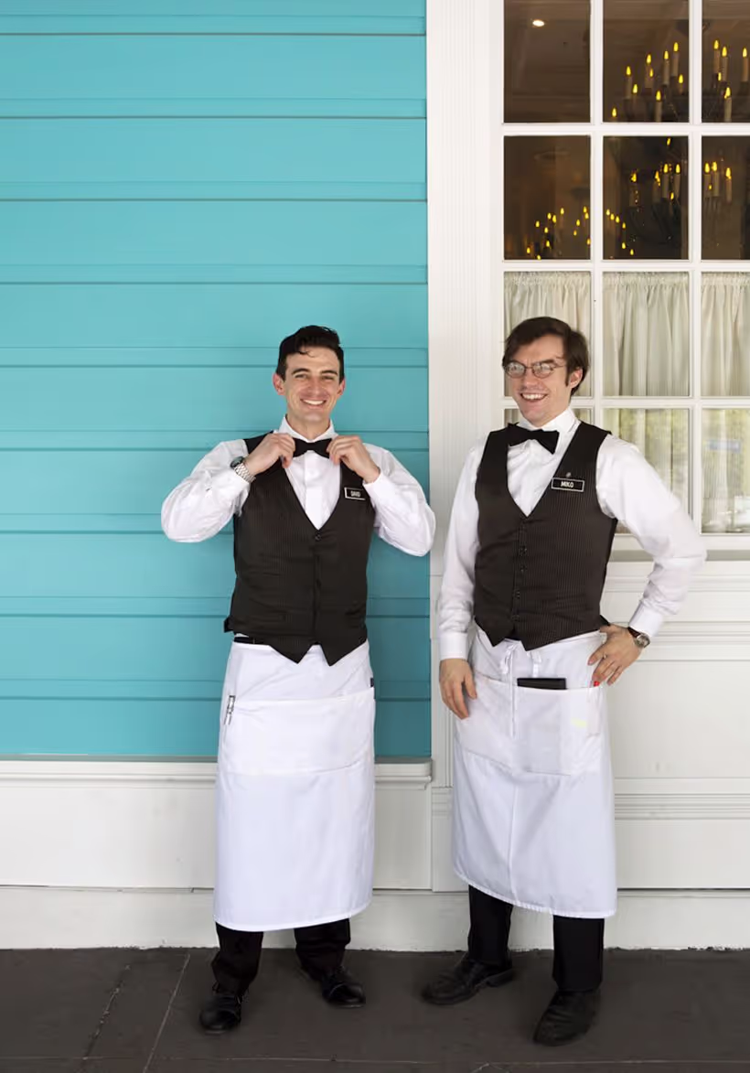 Servers in their vests and bowties stand outside of the Commander's Palace building.
