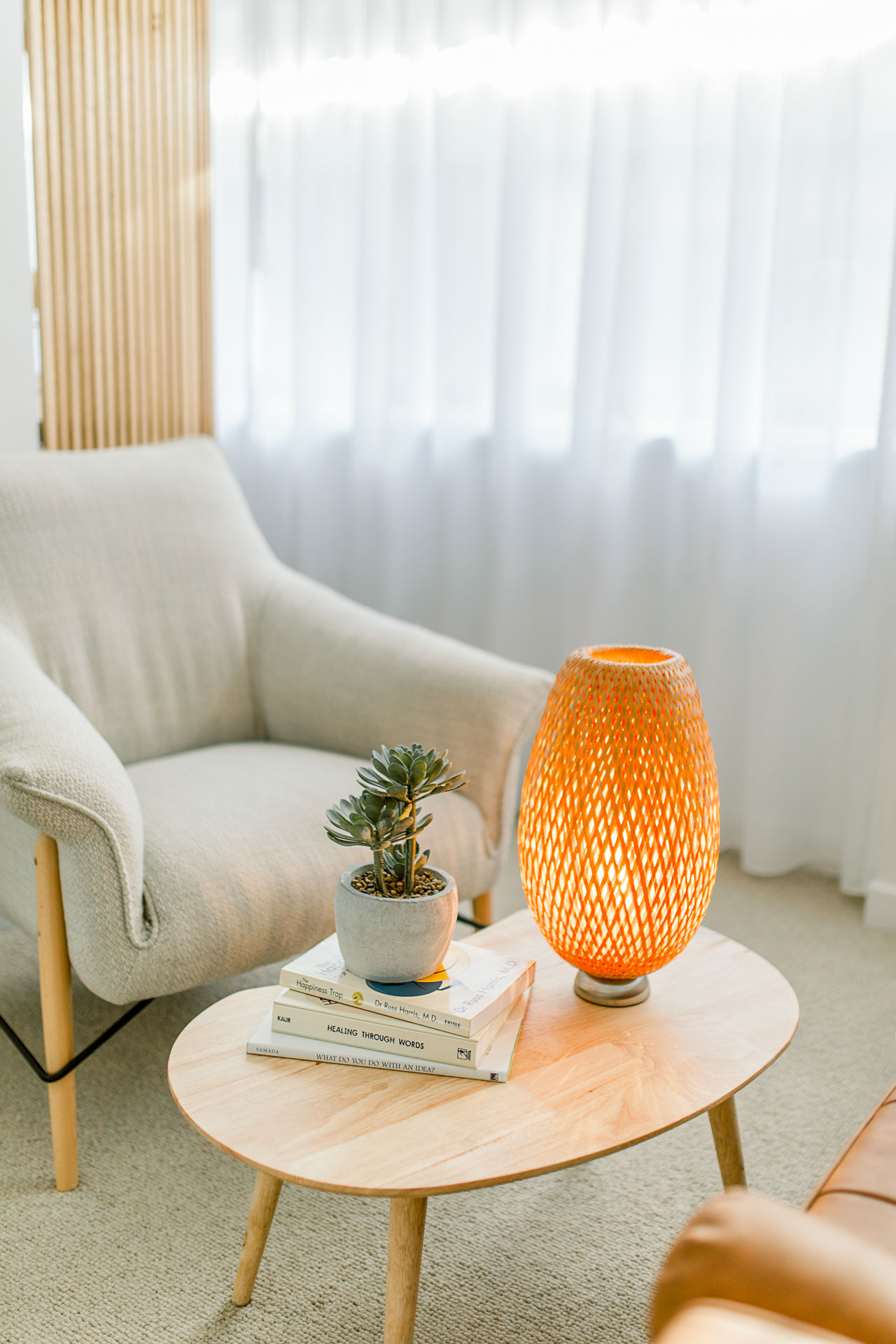 Cozy living room corner with beige armchair and glowing woven lamp