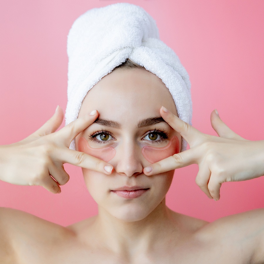 Une femme satisfaite avec des patchs de collagène sous les yeux, montrant un traitement anti-cernes efficace.