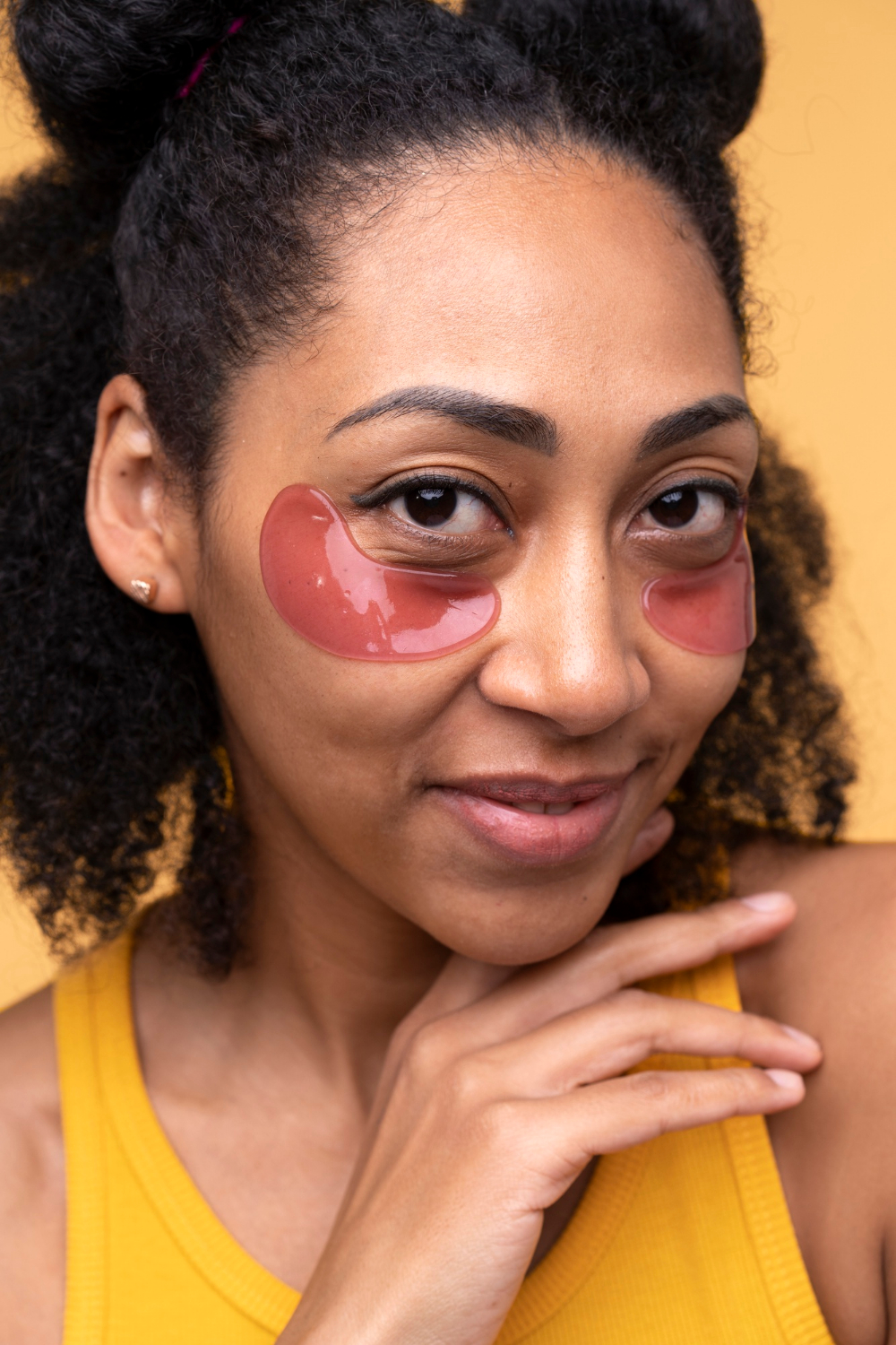 Portrait d'une jeune femme portant des patchs pour les yeux, illustrant un soin contour des yeux contre les cernes et les poches sous les yeux.