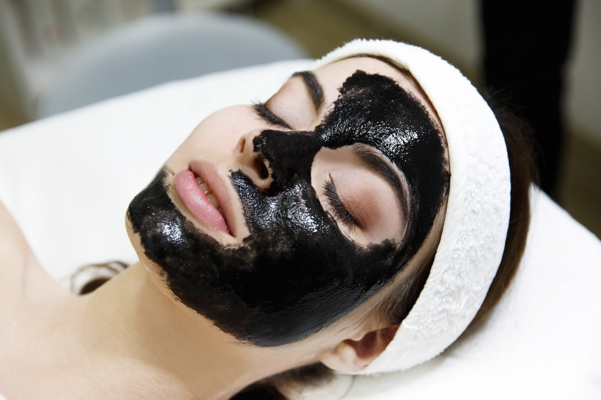 Femme allongée dans un salon de spa avec un masque noir appliqué sur le visage