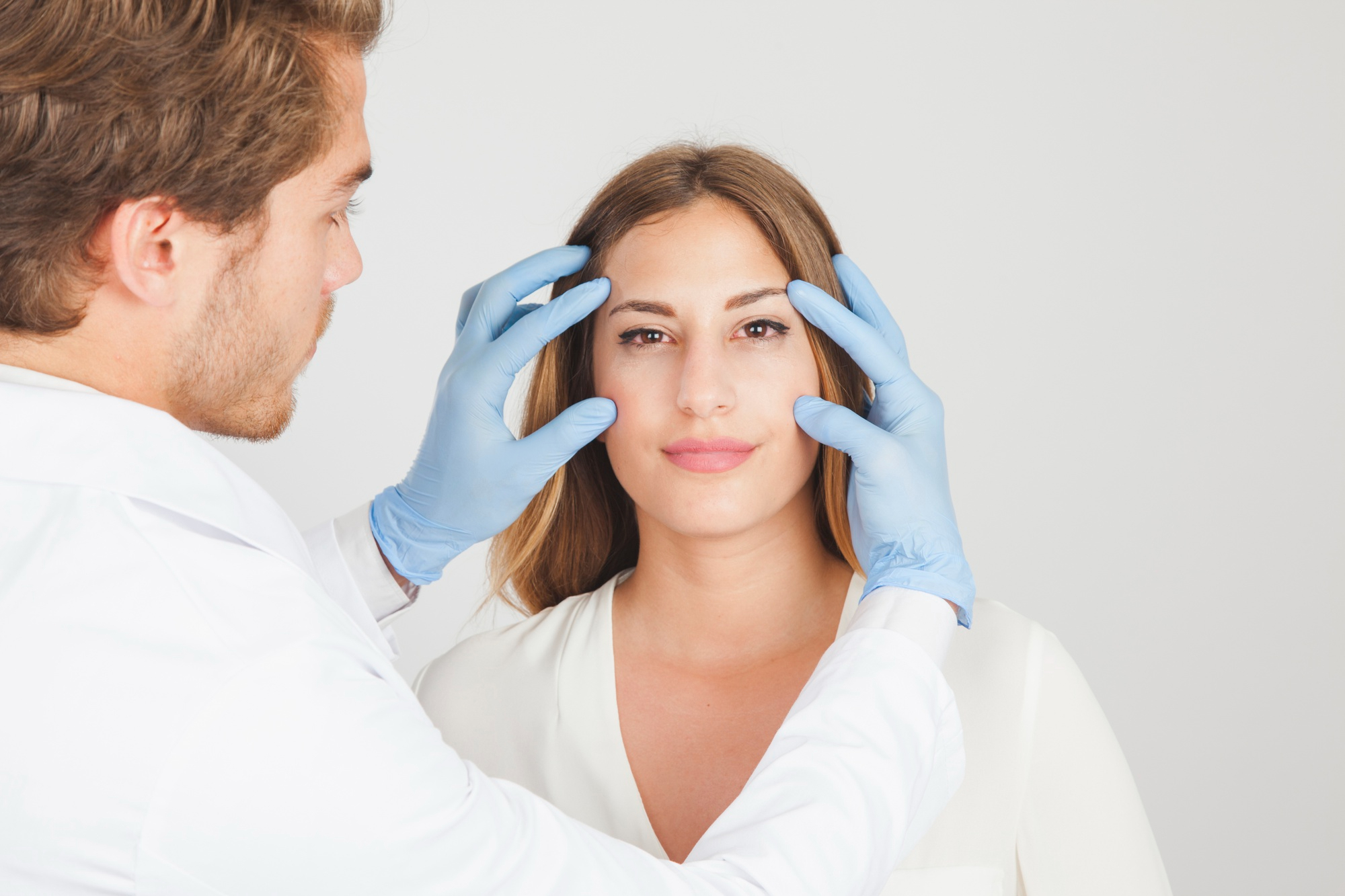 Professionnel en clinique médico-esthétique examinant le contour des yeux d’une patiente avant un traitement du visage à Montréal.