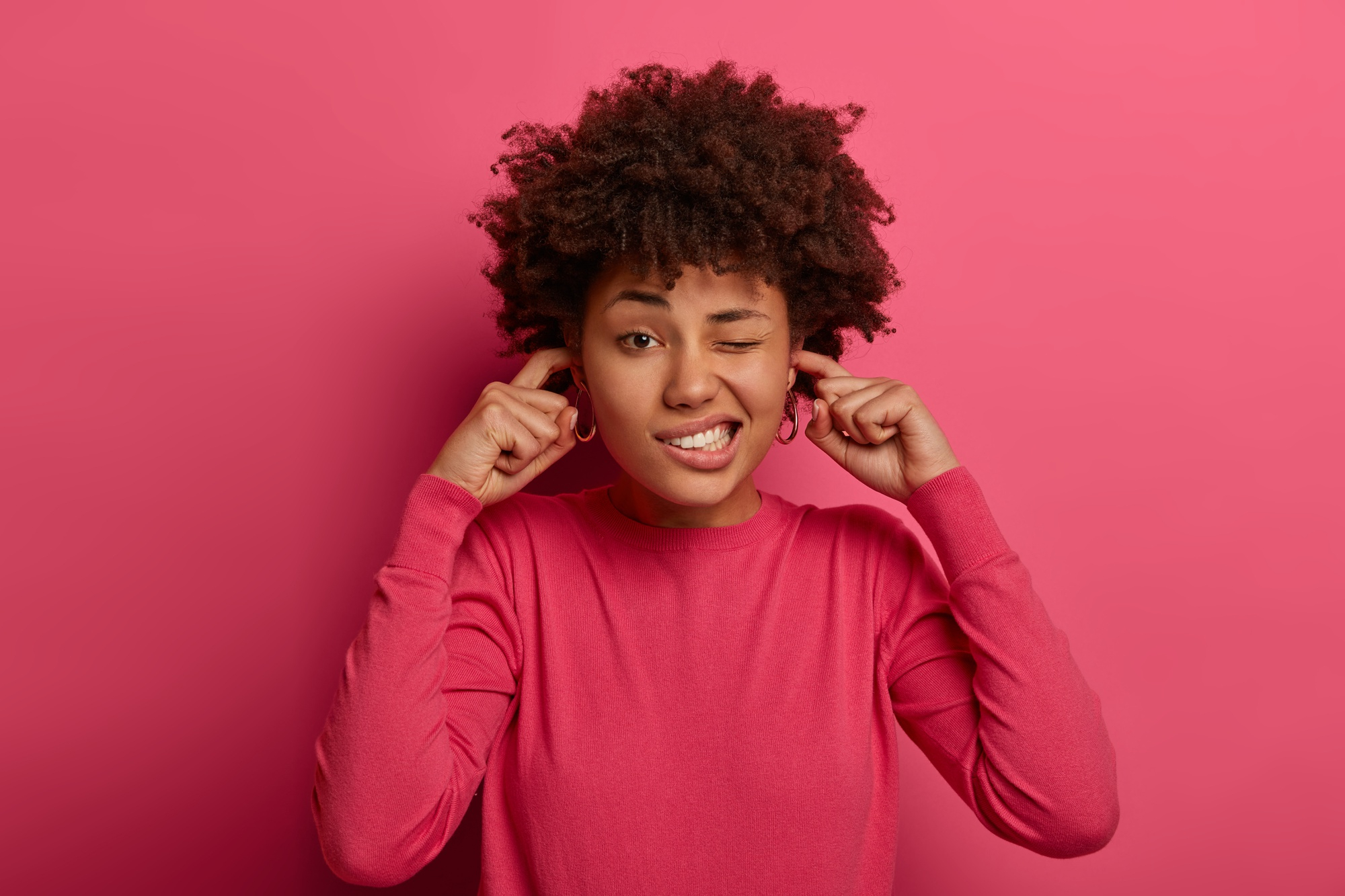 Jeune femme portant la main à sa mâchoire inférieure avec une expression d'inconfort, geste évocateur des douleurs liées au bruxisme au quotidien.