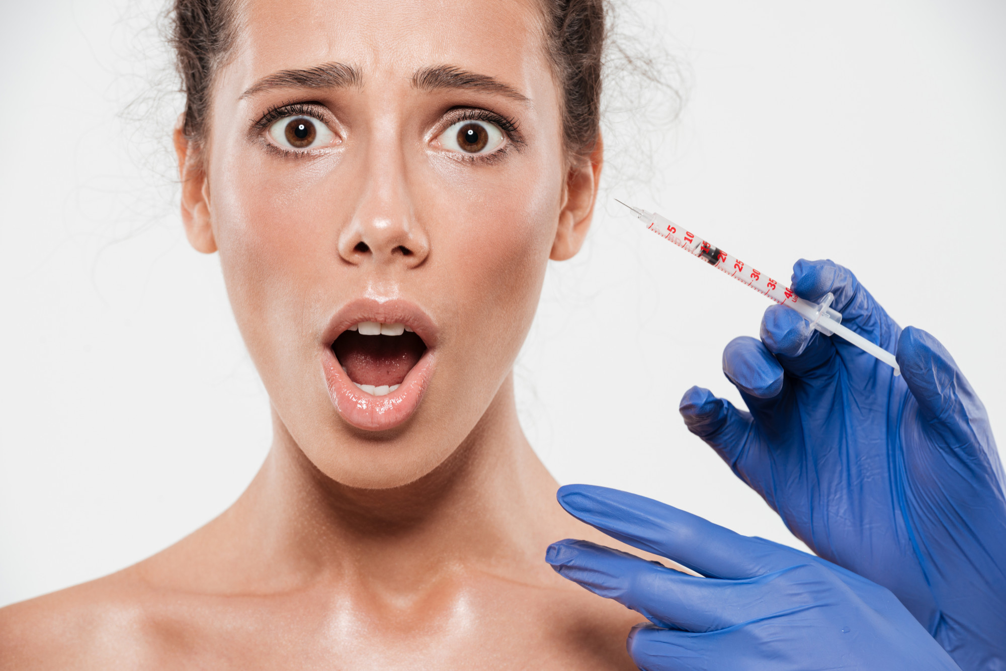 Young woman holding her lower jaw with a tense expression, reflecting the discomfort of bruxism before considering masseter botox treatment.