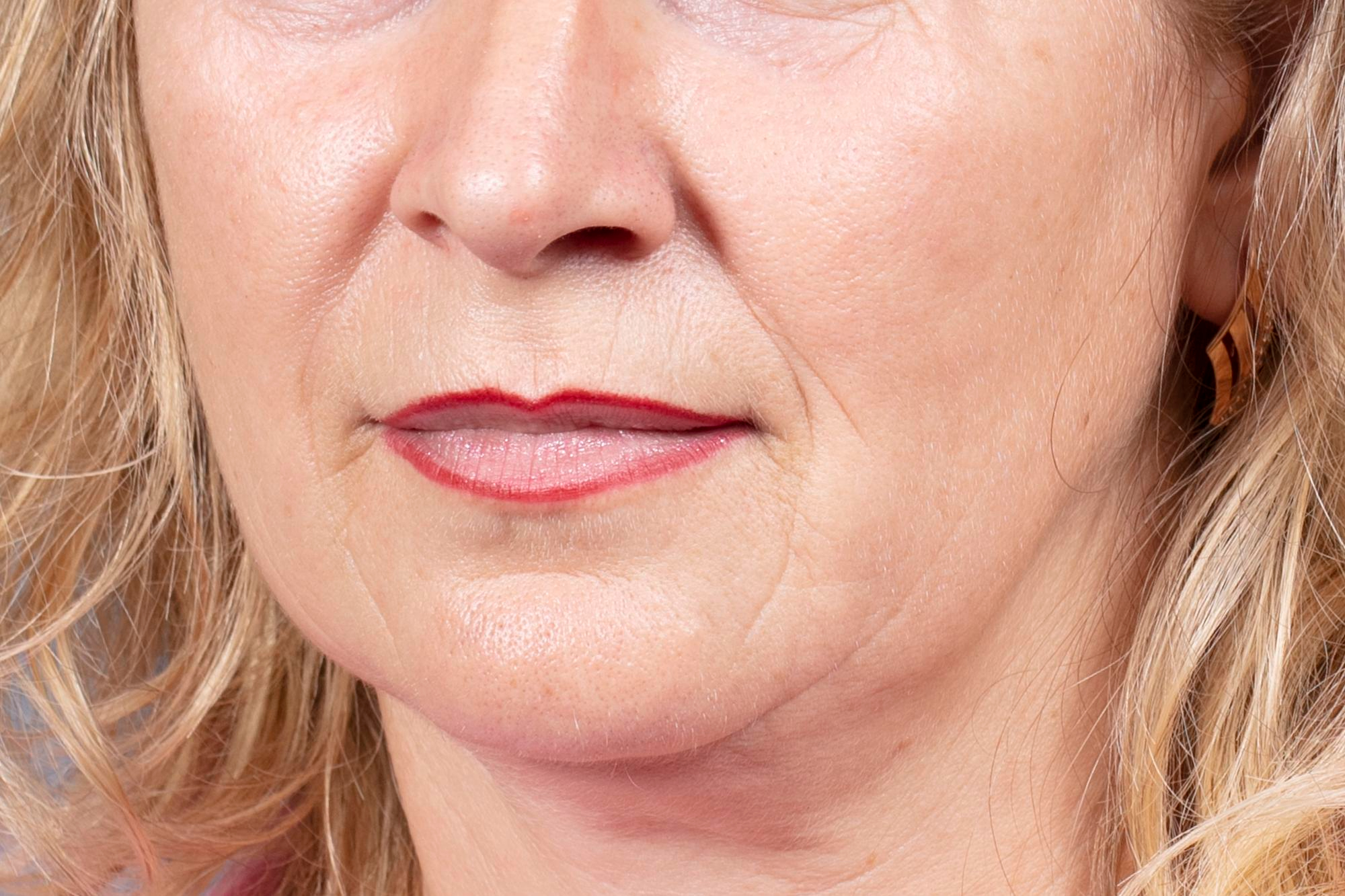 Gros plan du bas du visage d'une femme mature aux cheveux blonds montrant des rides du visage bien marquées autour de la bouche.