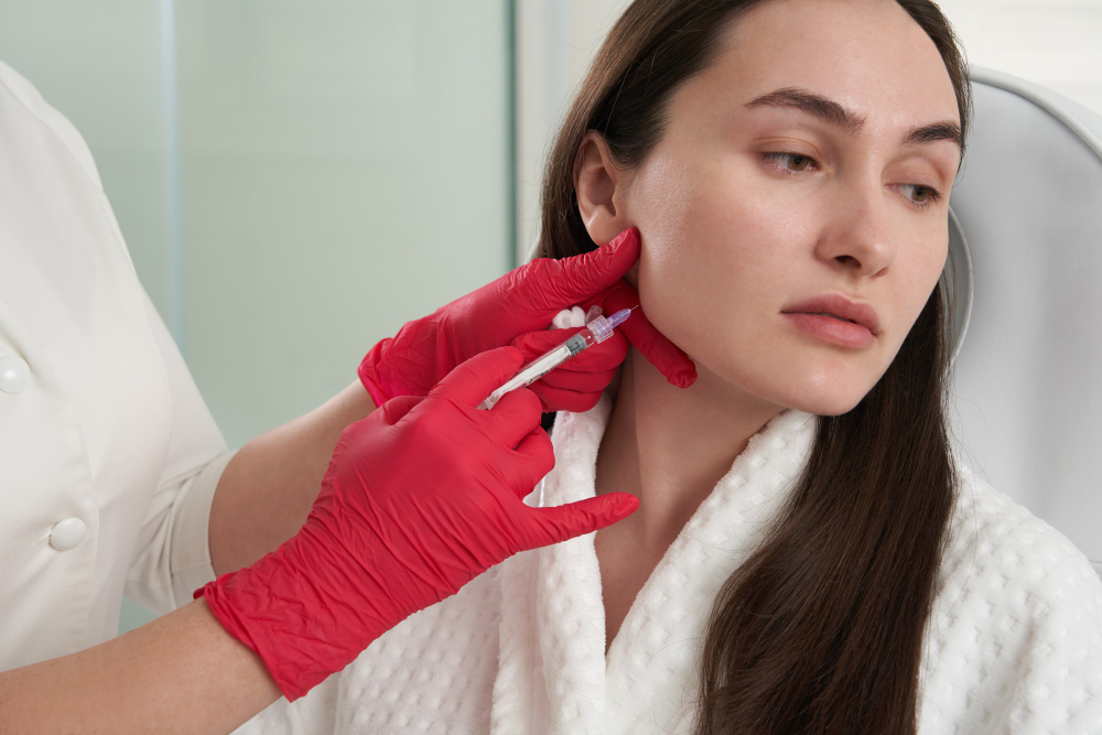 Professionnelle injectant la mâchoire dans le cadre d'un traitement du double menton à Montréal.