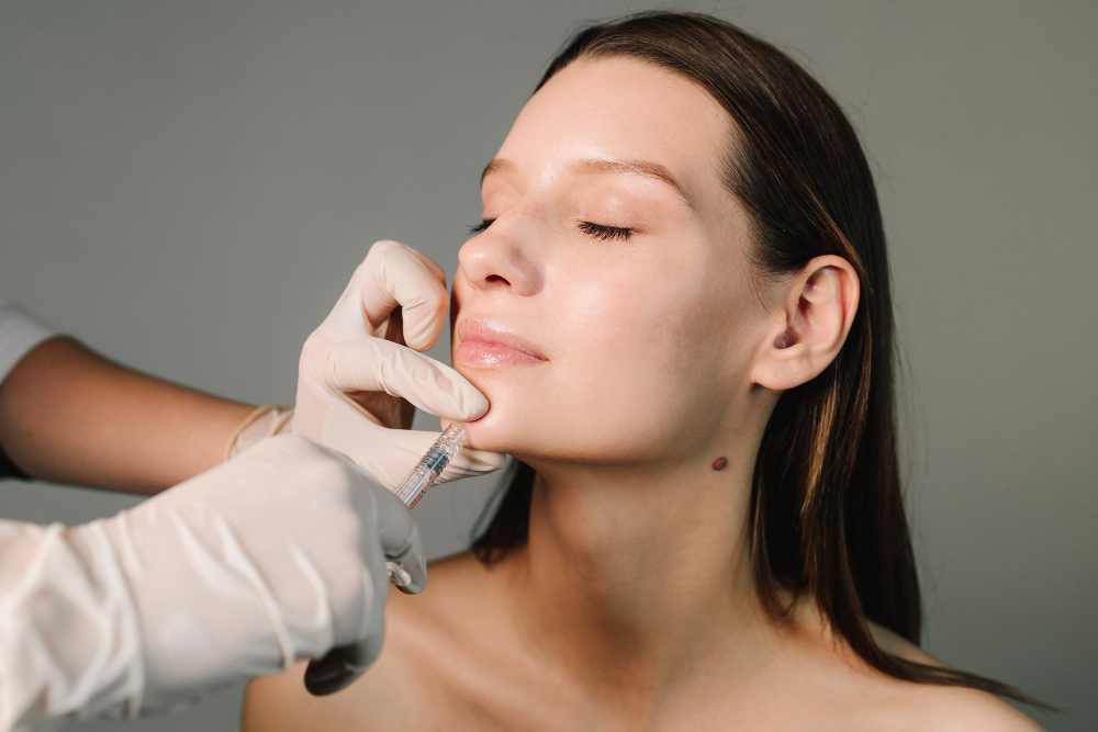 Main gantée effectuant un traitement injectable près du nez et de la lèvre supérieure.