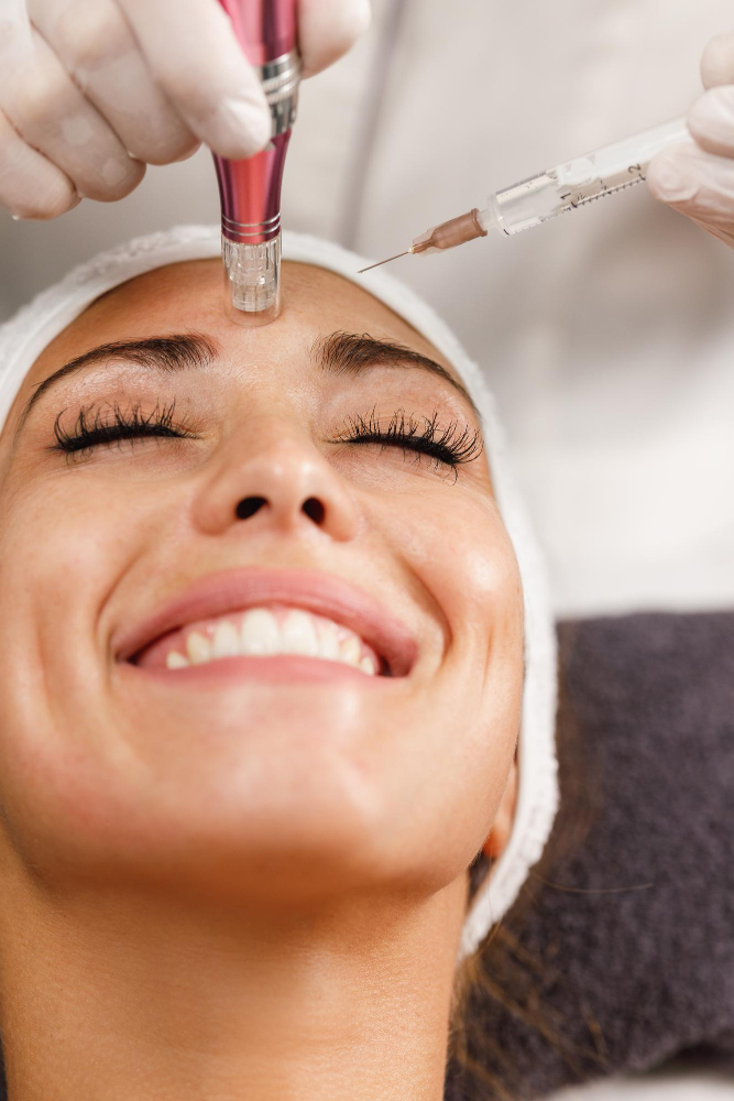 Professionnelle pratiquant le «microneedling» aux polyvitamines sur le front d'une cliente souriante.