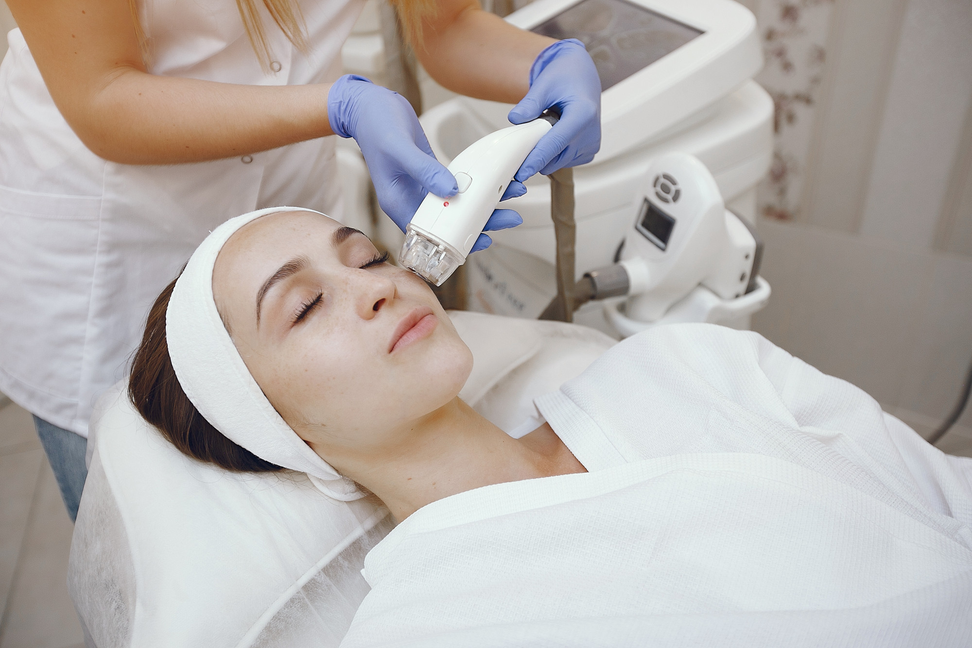 Esthéticienne effectuant un soin visage à la radiofréquence avec appareil professionnel en clinique de beauté