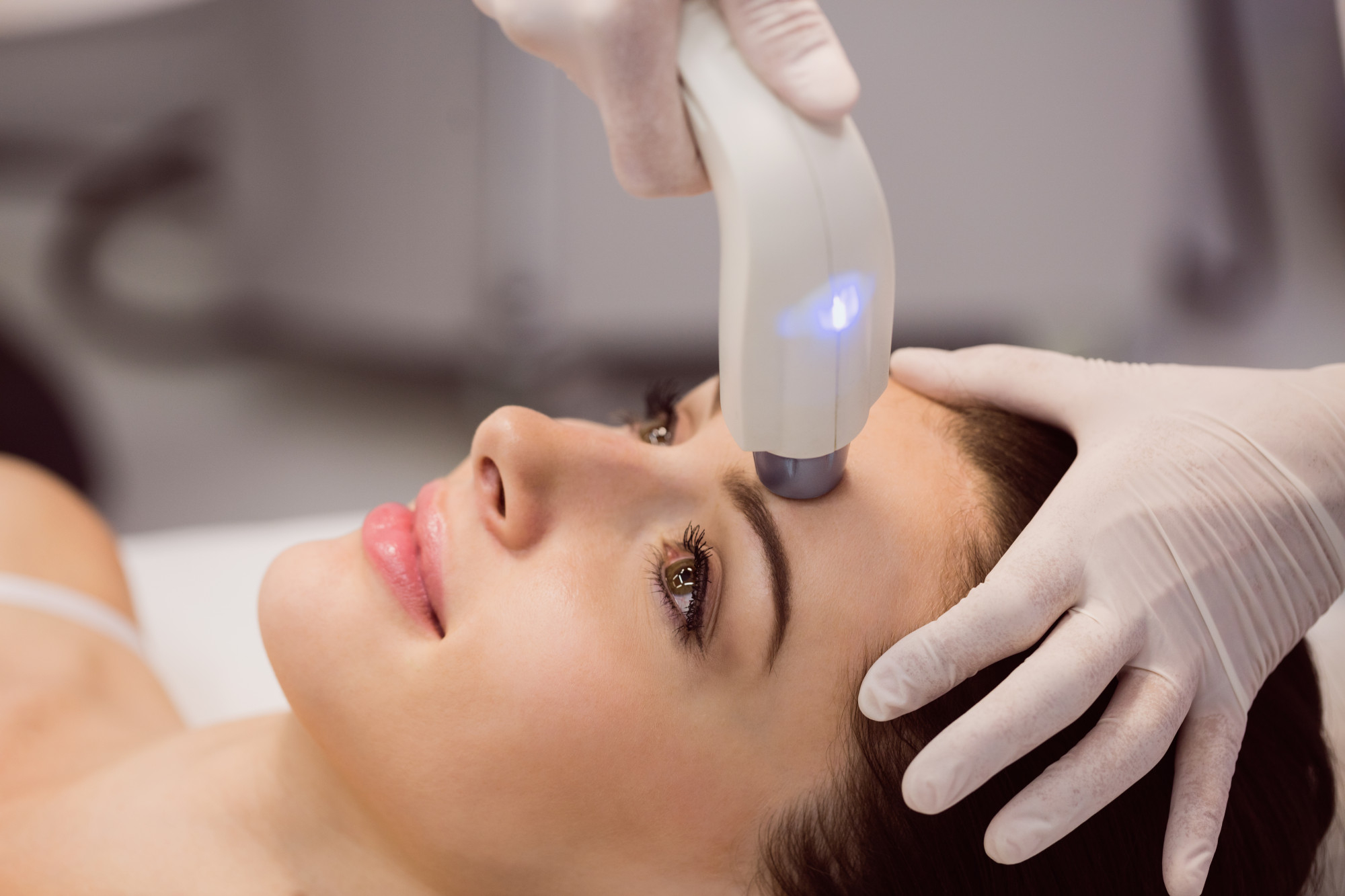 Traitement facial au laser LED bleu pour soin de la peau en clinique esthétique.