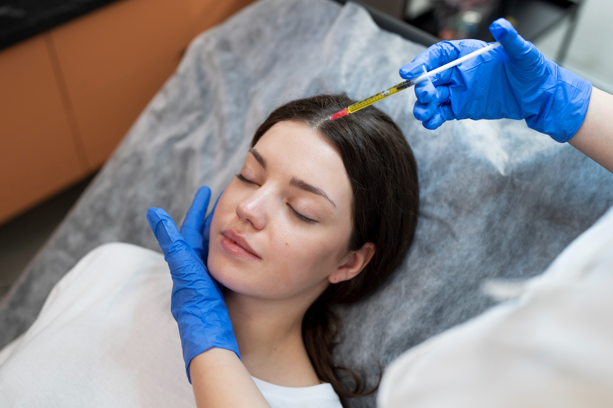 Mésothérapie capillaire à la seringue sur le cuir chevelu d'une patiente en clinique dermatologique.